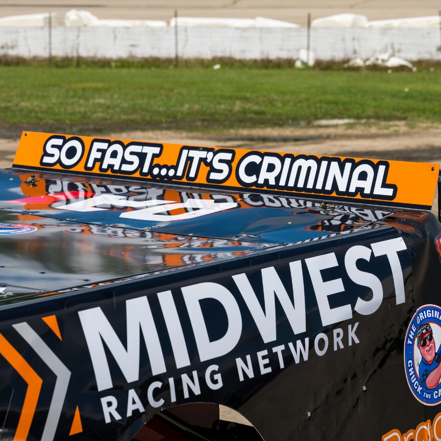 Close-up of the No. 23 short-track race truck roof spoiler reading "So Fast It's Criminal" above a Midwest Racing Network sponsor graphic